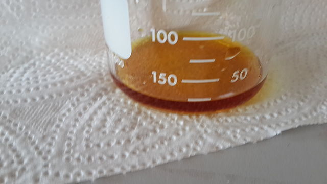 Photograph of the bottom of a beaker containing a small amount of iodine solution. The iodine solution is yellow-brown in colour. The beaker is on top of a paper towel.