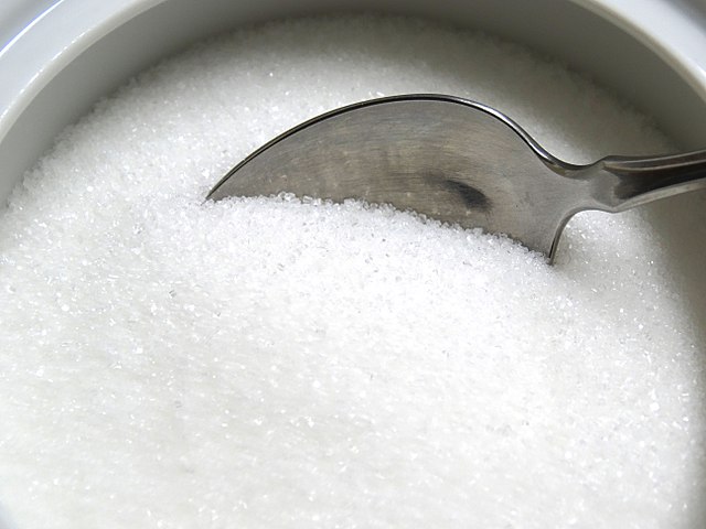 Photograph of a bowl of sugar with a spoon in it.